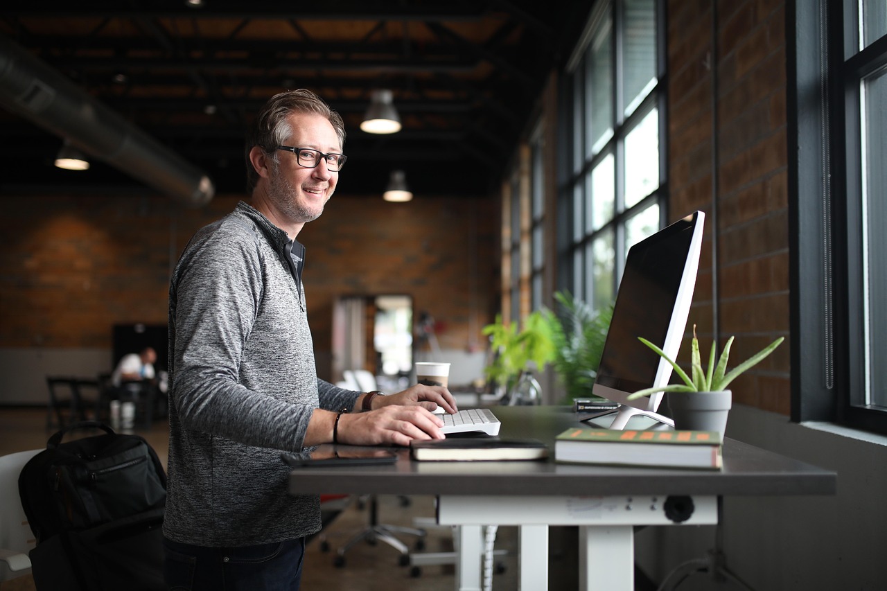Man standing at standing desk and smiling at camera