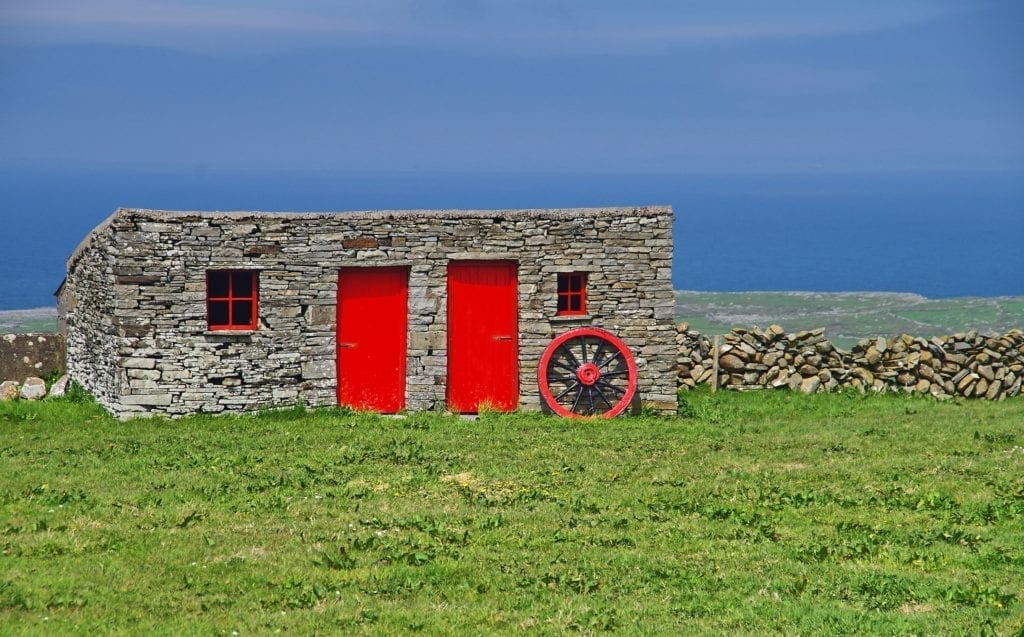 Old Irish stone cottage with red door and windows